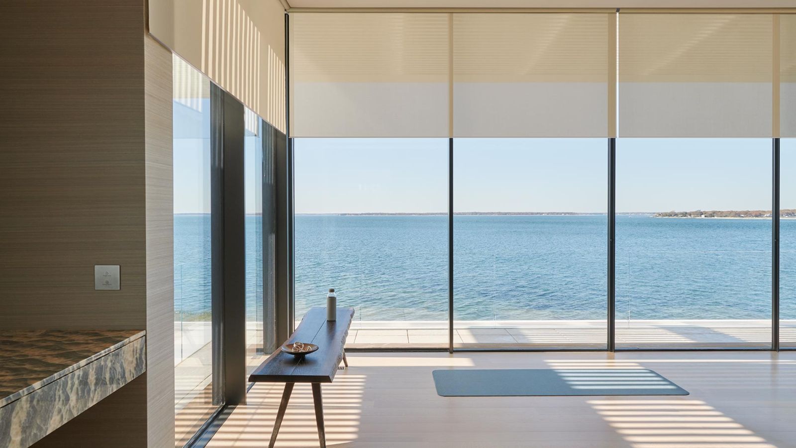 Minimalist room with floor-to-ceiling windows, yoga mat, and ocean view