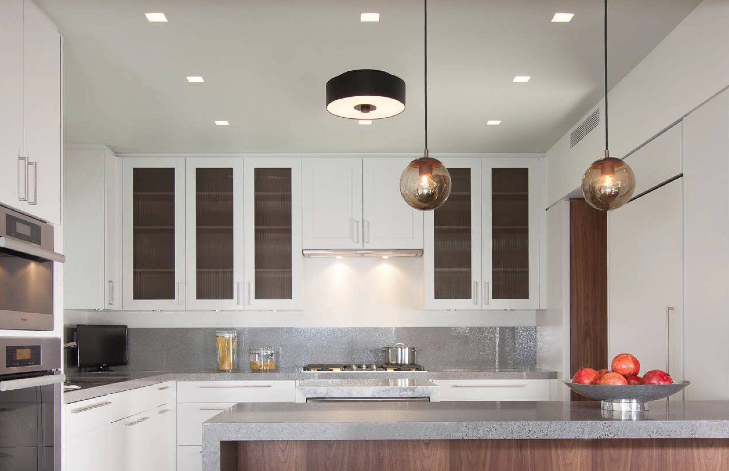 Modern luxury kitchen with layered lighting design, featuring pendant lights over the island and under-cabinet lighting