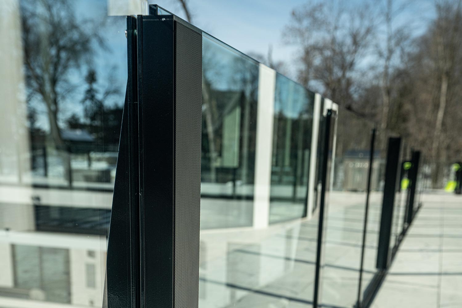 Sleek black speaker integrated into a modern glass balcony railing