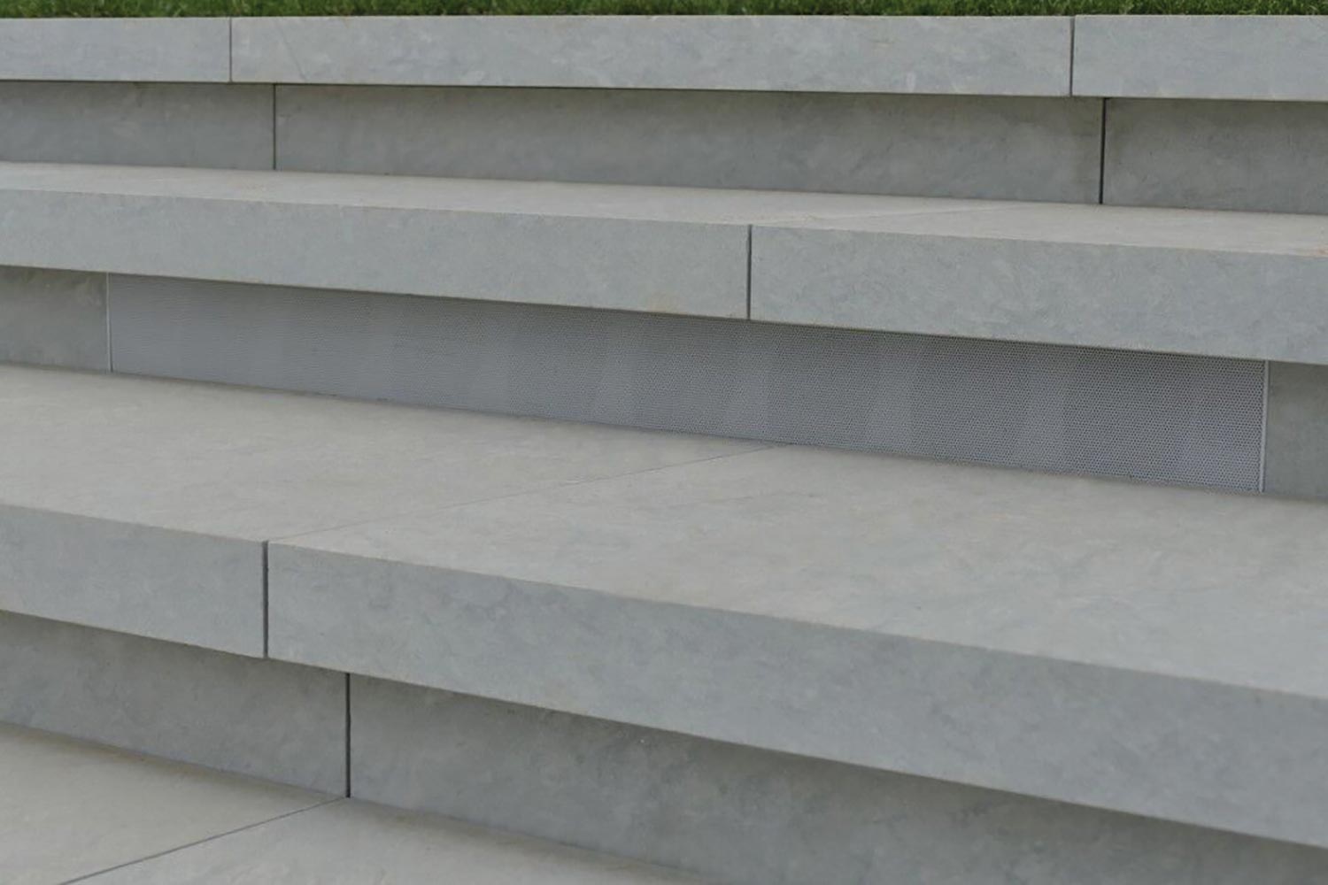 Long rectangular speaker grille built into stone outdoor stairs