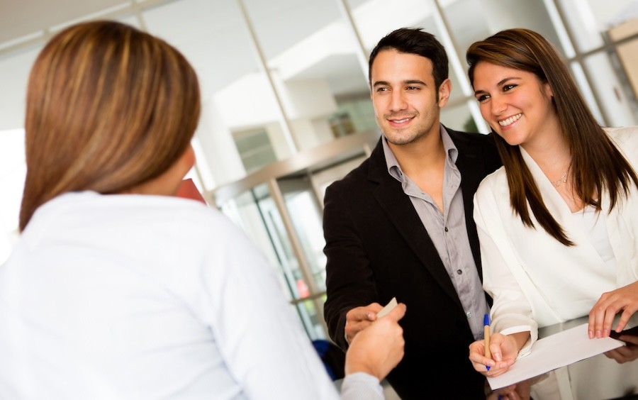 A couple signs paperwork and takes a business card from a professional.