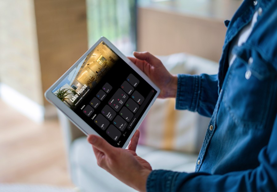 A person holding an iPad showing a control system for their Lake House.