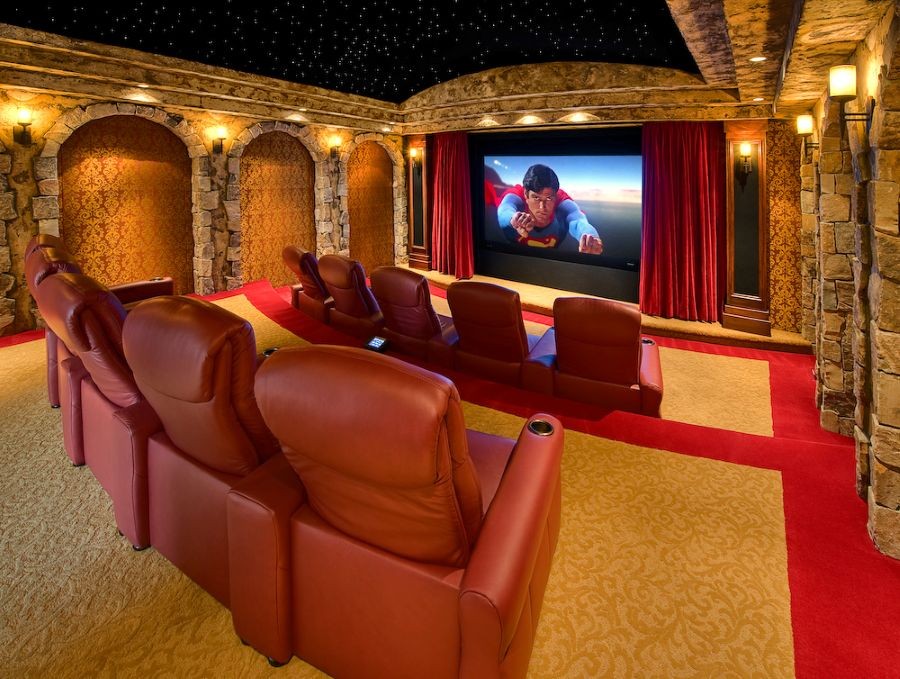 A beautiful luxury home theater with tiered seating, a fiber optic ceiling, and a large movie screen displaying Superman.