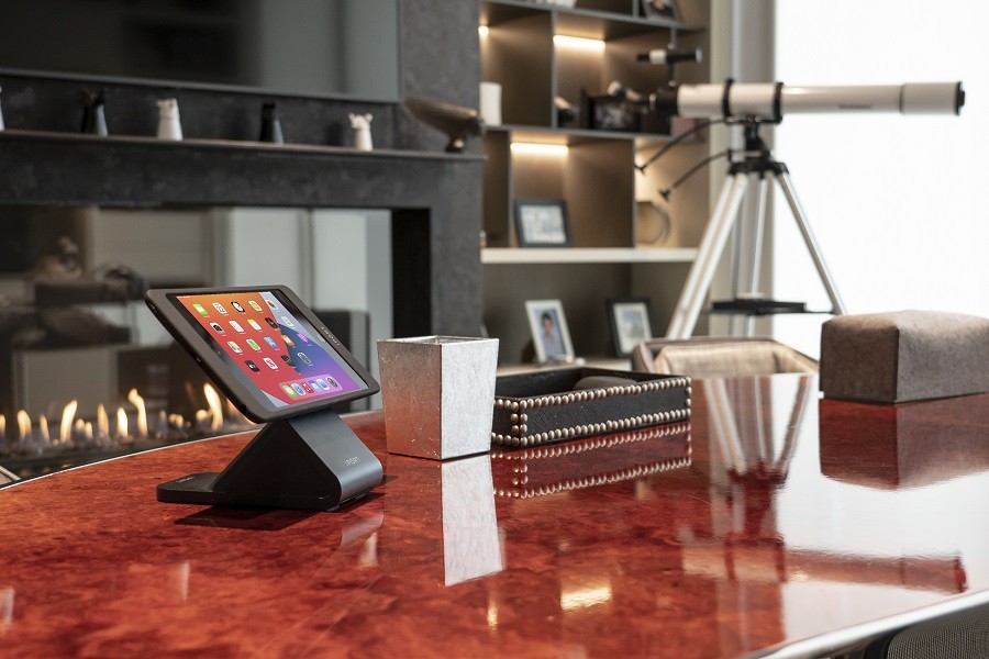 A Control4 touchscreen sits on a rosewood table with other elegant items. 
