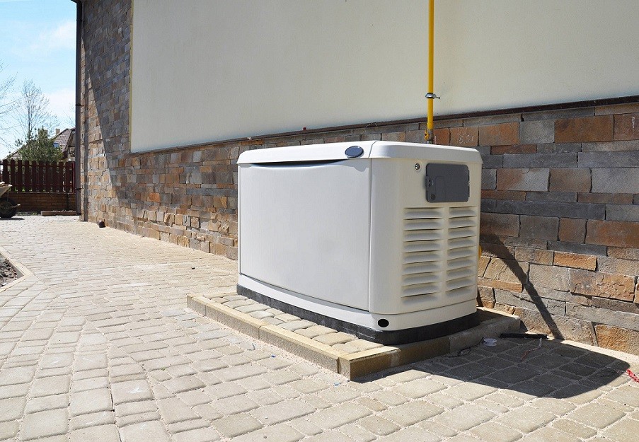 A home generator resting on a paver slab, which is also on a paver patio.