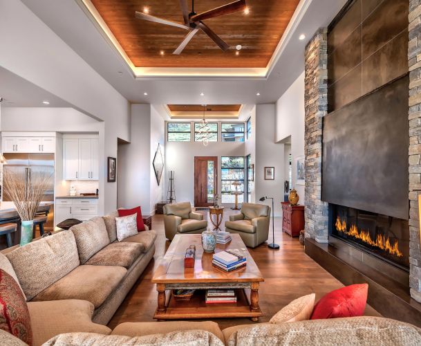 Spacious living room with a high wood-paneled ceiling, stone fireplace, and large sectional sofa.